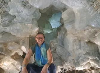 Kat sitting in front of large crystals in background